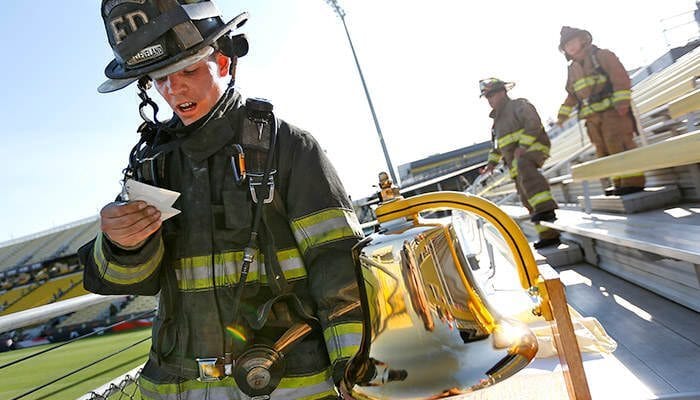 Kyle Koehler of the East Cleveland Fire Dept. reads the names of first responders killed in the Sept. 11, terrorist attacks as he rings the bell after 1 and a half laps during the 2nd Annual 9-11 Memorial Stair Climb on Friday, Sept. 11, 2015 in Columbus, Ohio. Hundreds of participants made two and a half laps around the stadium going up enough stairs to equal the 110 stories in each of the World Trade Center twin towers. (Chris Russell/The Columbus Dispatch via AP)