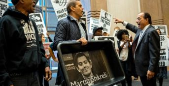 FILE - In this Thursday, Oct. 1, 2015, file photo, carrying an image of Turing Pharmaceuticals CEO Martin Shkreli in a makeshift cat litter pan, AIDS activists and others are asked to leave the lobby during a protest highlighting pharmaceutical drug pricing. Shkreli, the former hedge fund manager under fire for buying a pharmaceutical company and ratcheting up the price of a life-saving drug, is in custody following a securities probe, Thursday, Dec. 17, 2015. (AP Photo/Craig Ruttle, File)