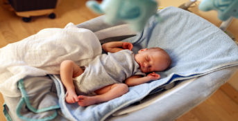 newborn boy sleeping in bouncer chair and dreaming