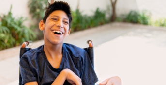 A child with cerebral palsy smiles at the camera