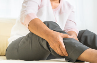 older woman rubbing calf muscle in pain