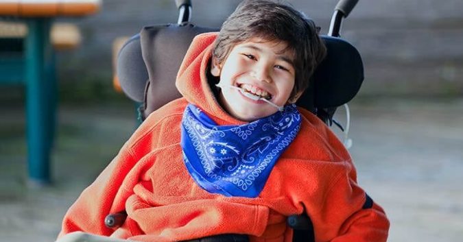 A child with cerebral palsy smiles at the camera