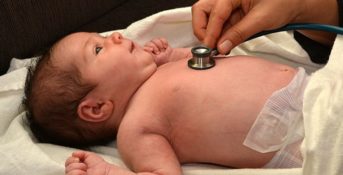 A doctor uses a stethoscope to listen to a baby's heart
