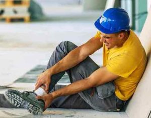 A construction worker holds his injured ankle