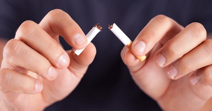 close up of hands breaking a cigarette in half