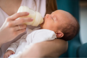 mother feeding her newborn baby a bottle