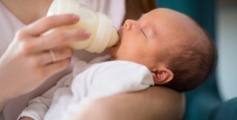 mother feeding her newborn baby a bottle