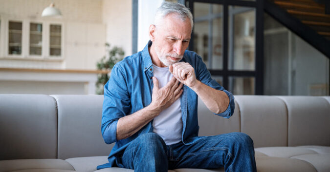 A man coughing and holding his chest