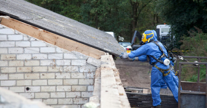 Worker removing asbestos-containing roof material