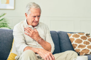 An older man holds his hand over his chest