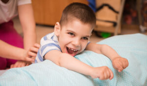 A young boy with CP smiles at the camera