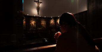 A woman kneeling before a crucifix