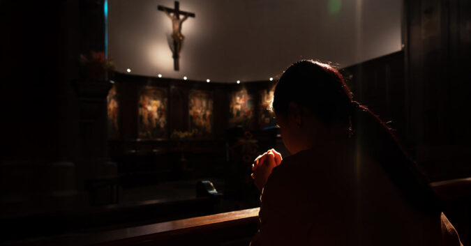 A woman kneeling before a crucifix