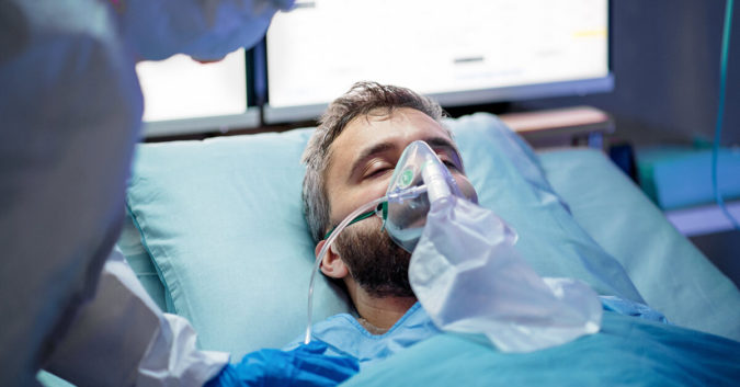man laying on hospital bed with ventilator