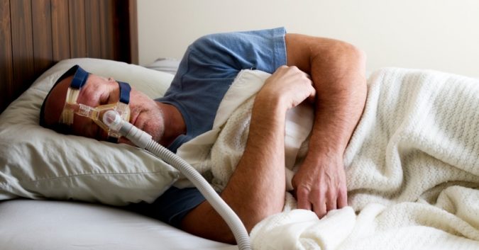 man-sleeping-in-bed-with-sleep-apnea-mask