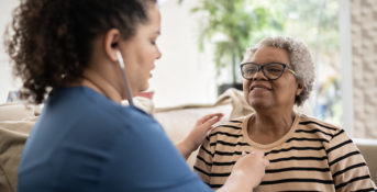 Nurse listens to patient's lungs with stethoscope