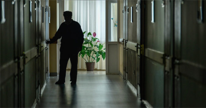 shadowy image of man standing in nursing home hallway