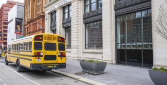 landscape shot of city buildings and a yellow school bus