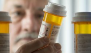 A man inspects the label on a prescription pill bottle. 