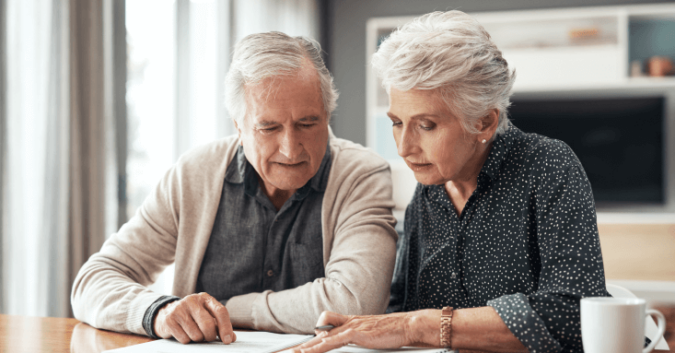 An older couple looks over documents at their table