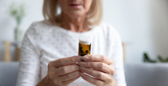 older woman looking at a prescription pill bottle