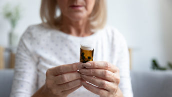 older woman looking at a prescription pill bottle