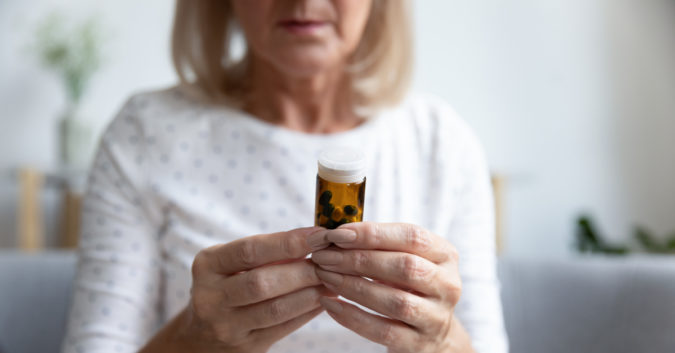 older woman looking at a prescription pill bottle