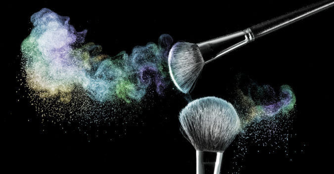 two makeup brushes covered in powder cosmetics