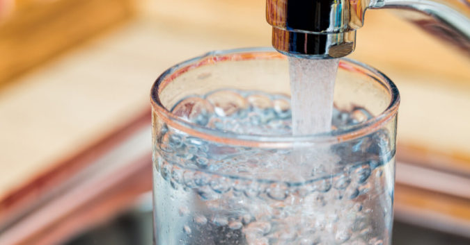 close up of a glass cup being filled with tap water