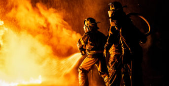 two firefighters trying to put out a fire