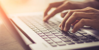 close up of hands typing on a laptop