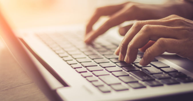 close up of hands typing on a laptop