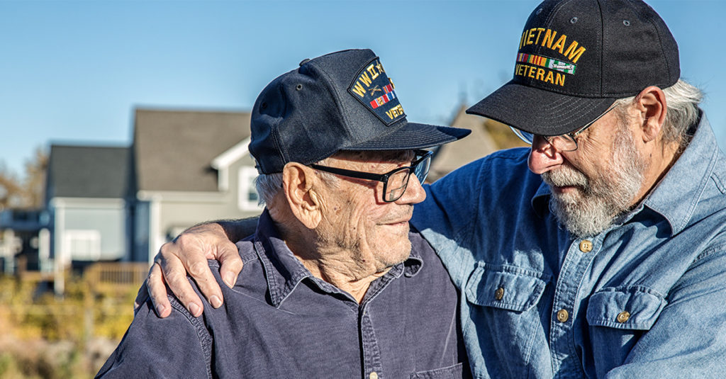 Two male veterans smiling at each other